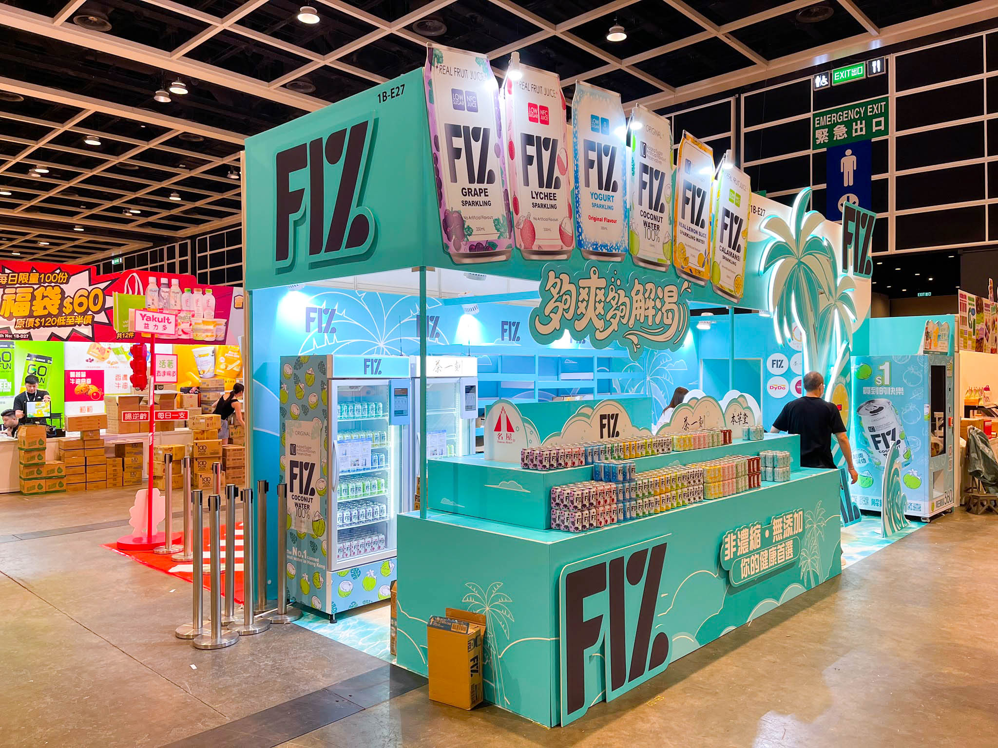 Completed FIZ booth at HKTDC Food Expo 2026 featuring product counters, suspended beverage packs, palm tree, timed challenge and vending machine